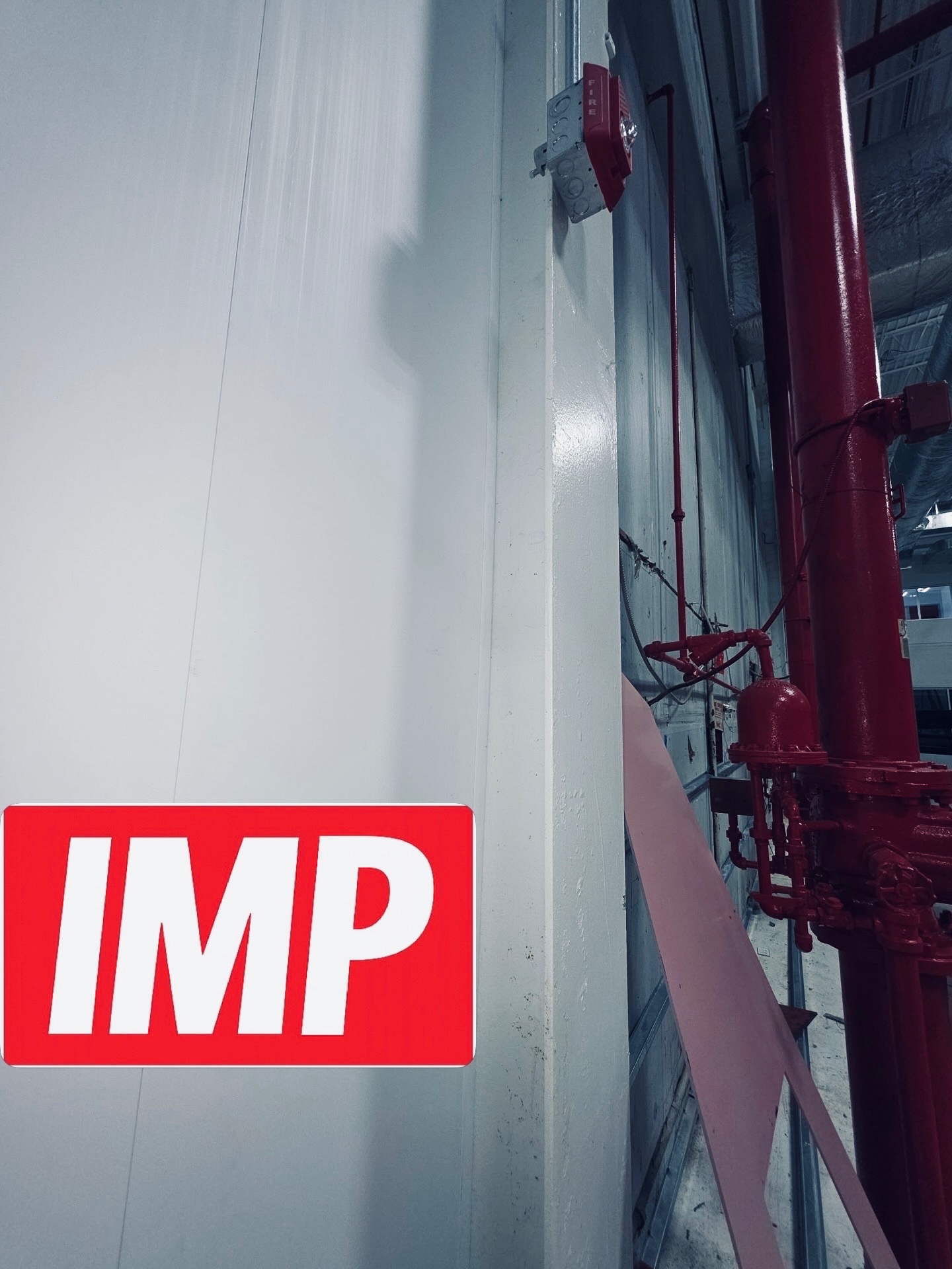 IMP logo on finished panel wall with red pipe system